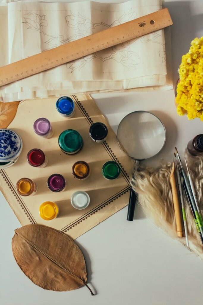 Top view of art supplies including paints, brushes, and flowers, ideal for creative projects.