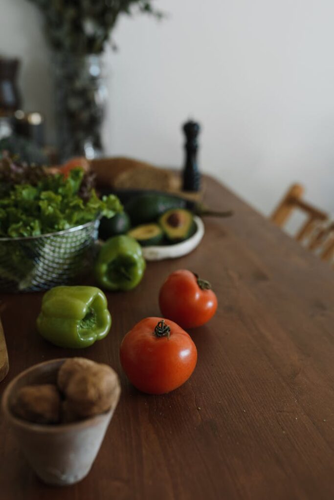 A selection of fresh vegetables including tomatoes and bell peppers on a wooden table.